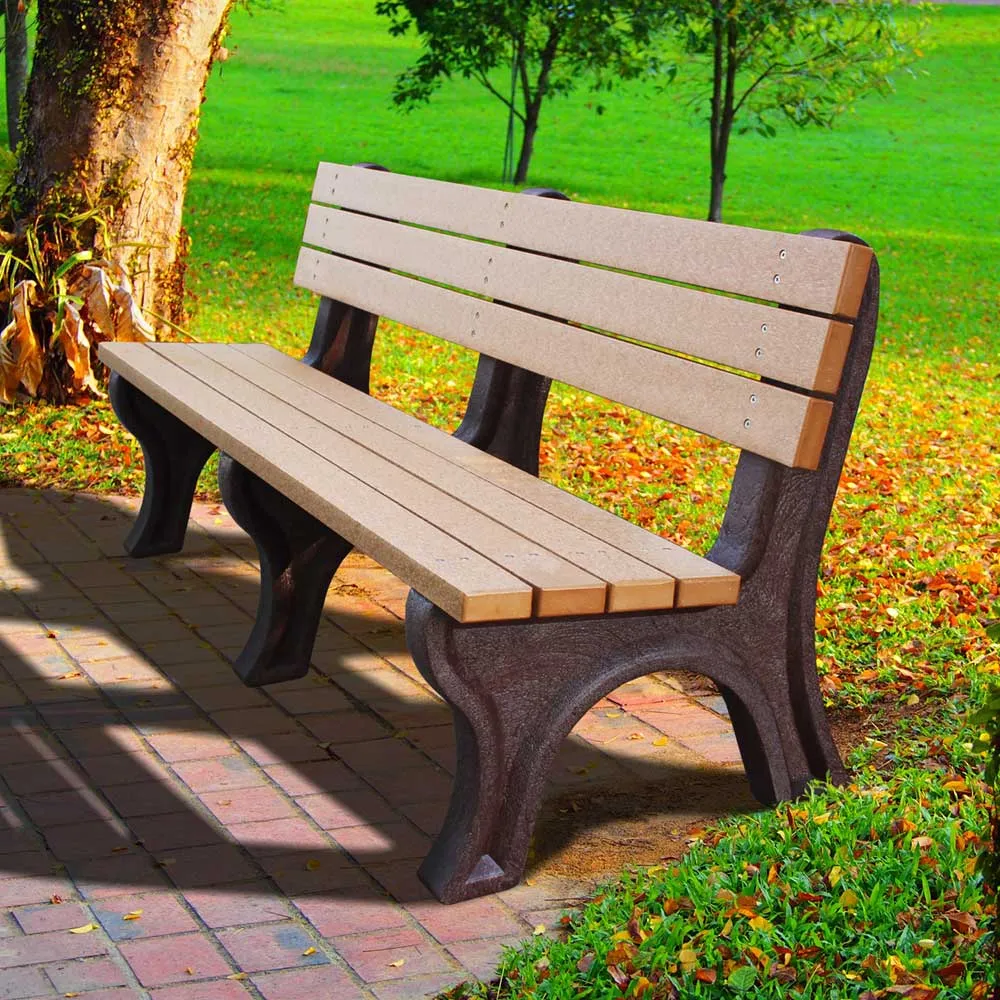 A weathered wooden park bench beside a tree in a green park.